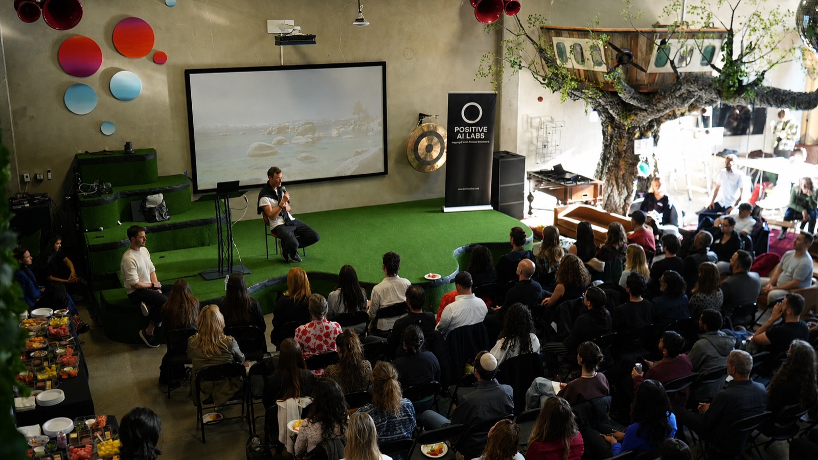 Jonatan Littke speaking on stage at a fireside chat, wide shot with audience